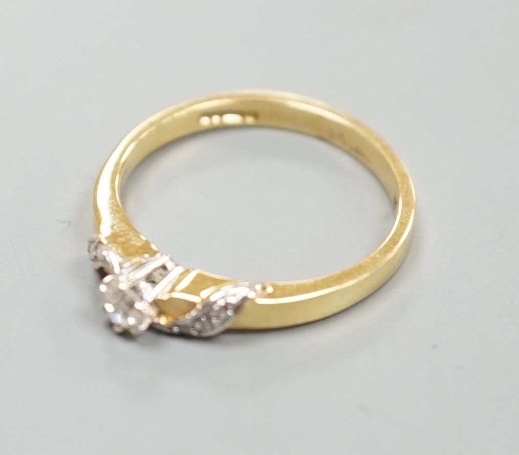 A modern 18ct gold and single stone diamond ring, with diamond chip set 'crossover' shoulders, size M/N, gross weight 2.8 grams.